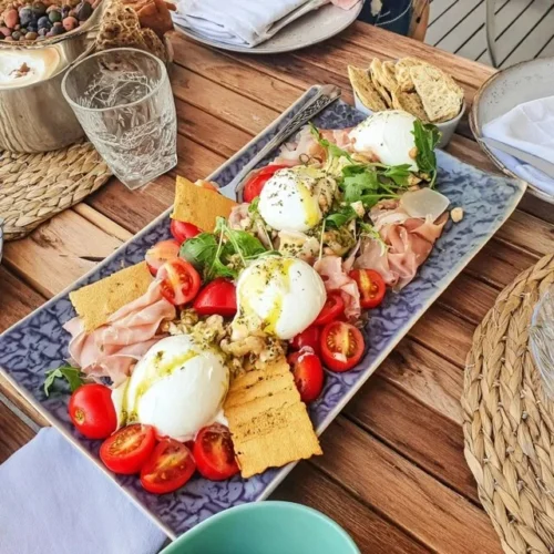 Piatto di burrata con pomodori freschi e cracker croccanti per cena tra amici
